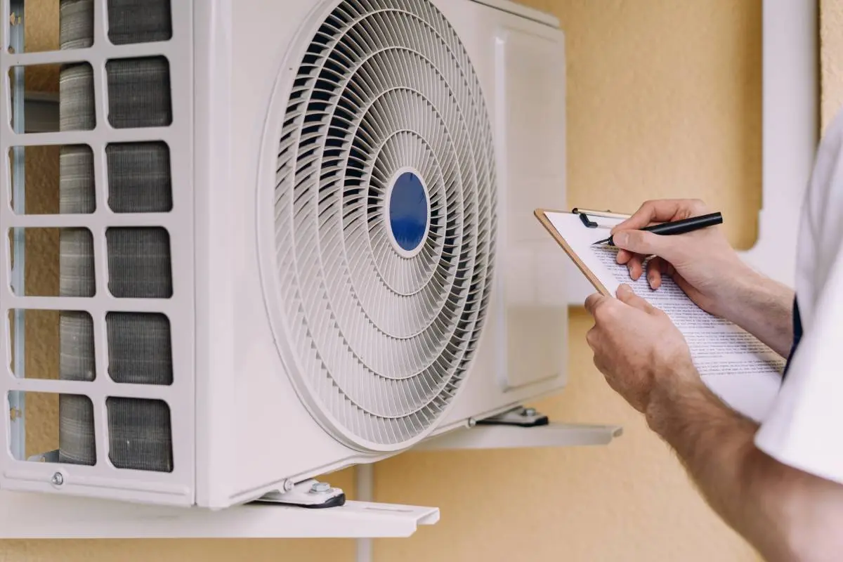 HVAC contractor holding a clipboard inspecting an HVAC install on a home
