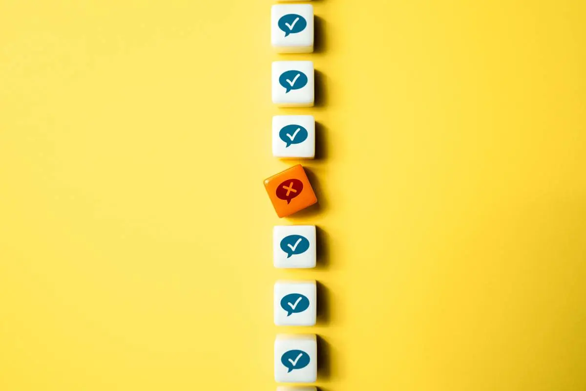 a line of white blocks with blue dialogue icons and white checkmarks in the middle broken up by an orange block with a dialogue icon and an X in the middle of it against a yellow background