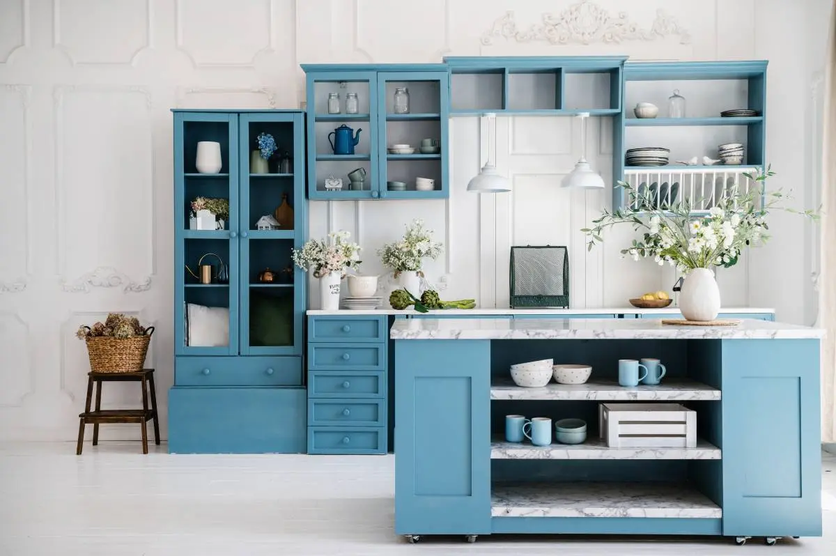 a rustic kitchen with marble countertops and blue cabinetry with ample storage