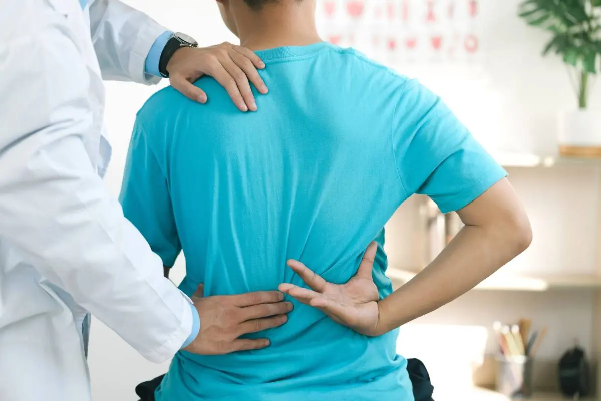 man in a blue shirt receiving a bank adjustment from a chiropractor 