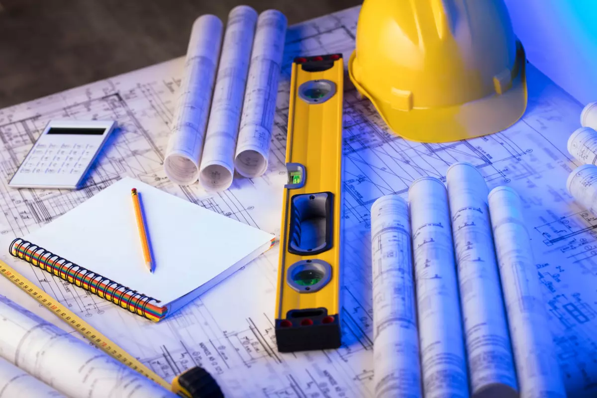 Close up on general contractor tools like hard hat, level, blueprints, tape measure