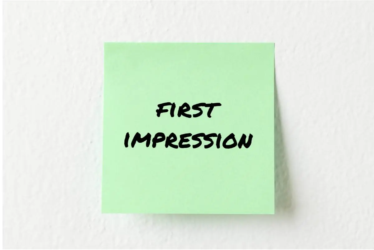 first impression written with a black sharpie on a green post it stuck to a white wall