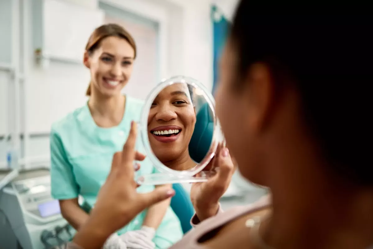 Smiling dental patient looking at teeth in mirror