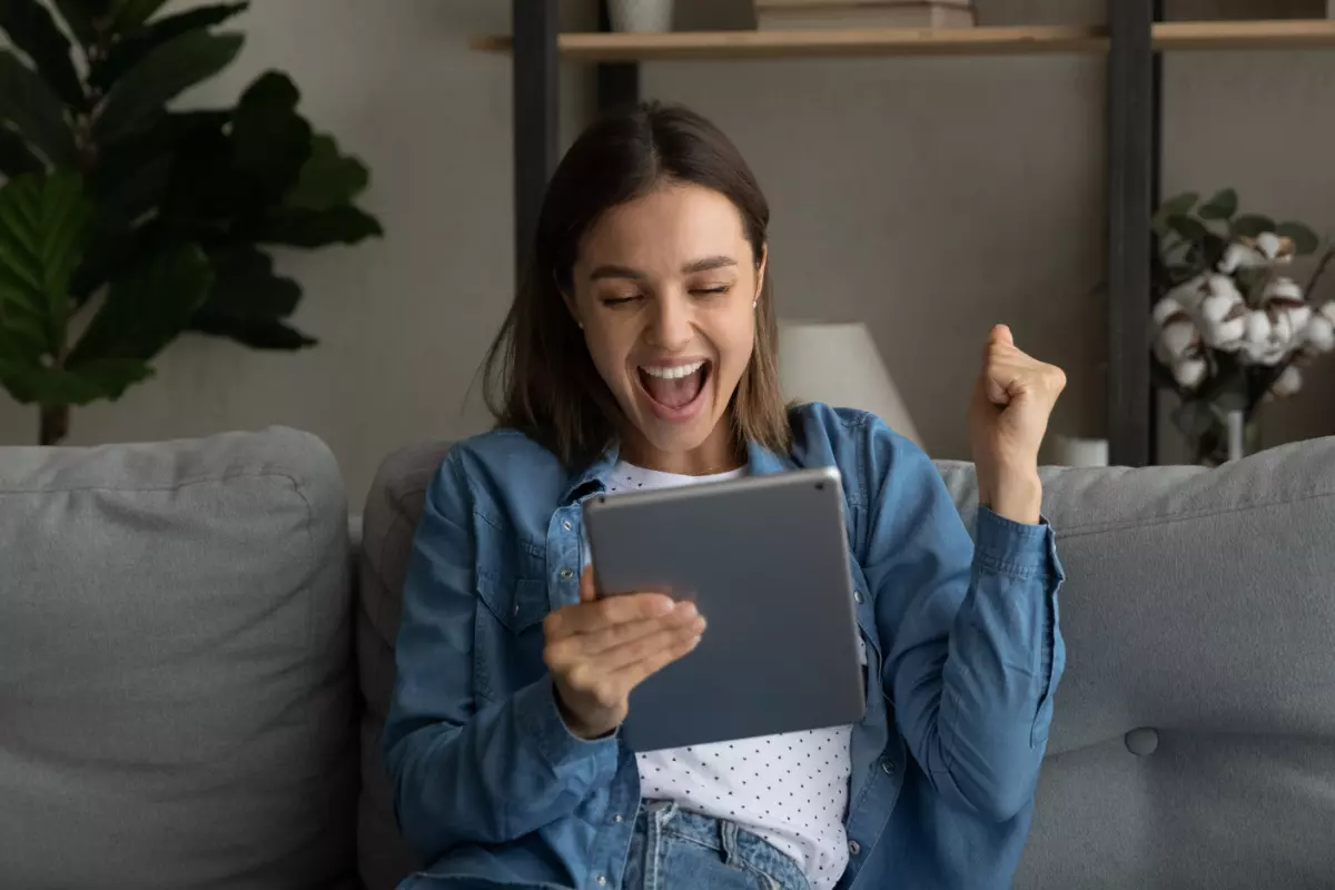 Happy consumer holding tablet with loan approval information