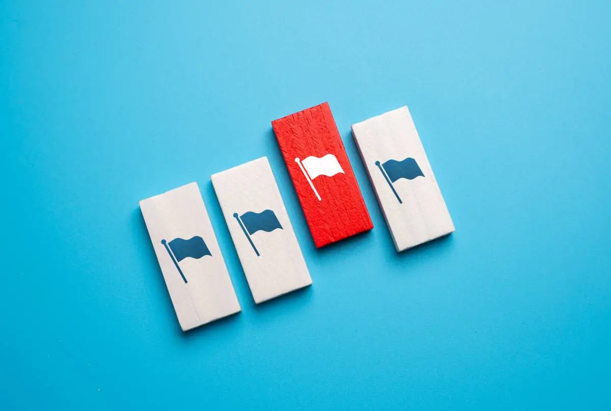 a red block with a white flag alongside white blocks with blue flags against a team background