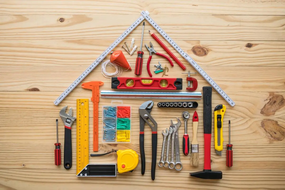 remodeling tools for a contractor arrange in the shape of a house laying flat on a wooden table