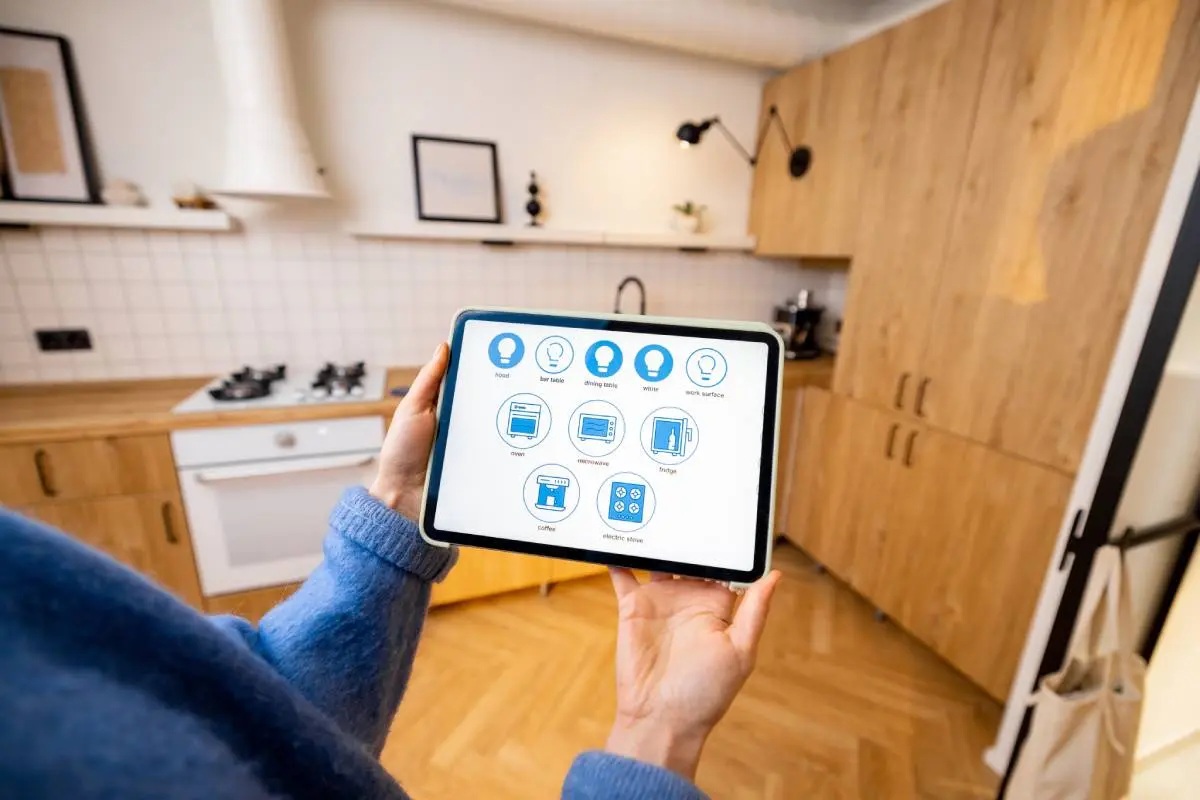 a woman holding a tablet with all the controls to her smart kitchen
