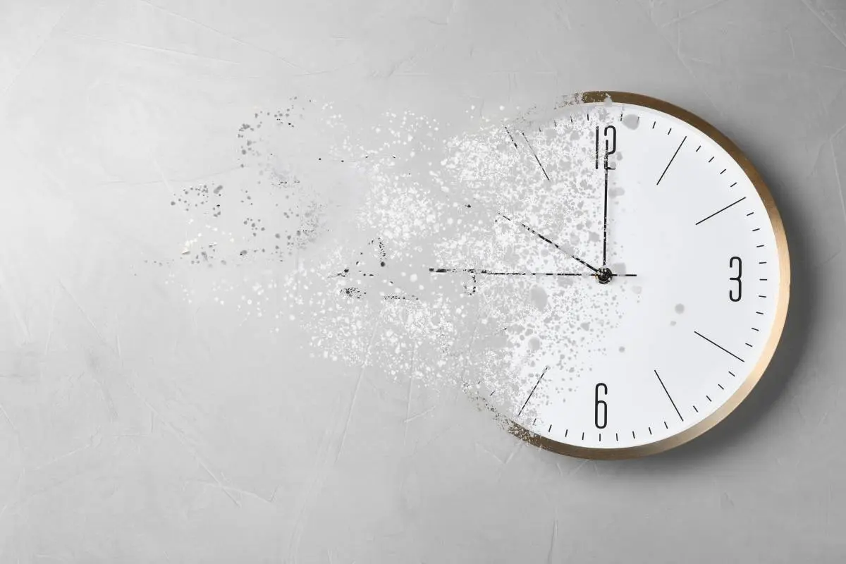 ticking clock exploding into pieces against a gray wall